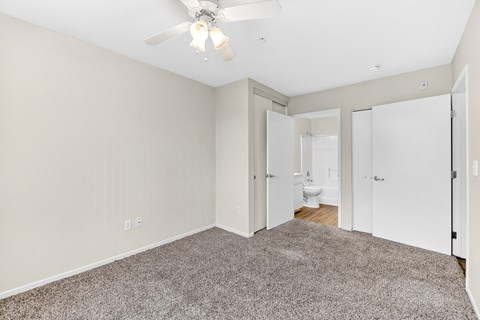 A spacious room with a ceiling fan and carpeted floor.