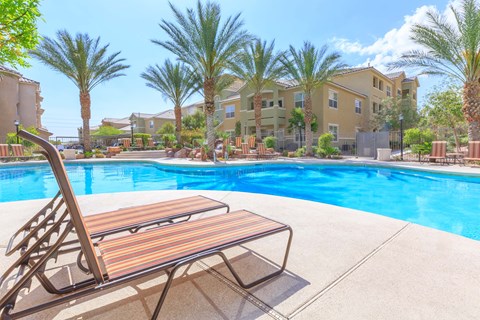 A poolside bench overlooks a pool and palm trees.