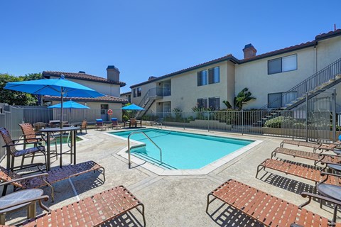 a swimming pool with chairs and umbrellas in front of a building