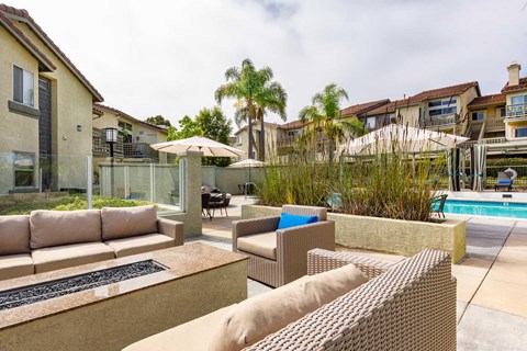 A patio with a couch, chairs, and a pool.