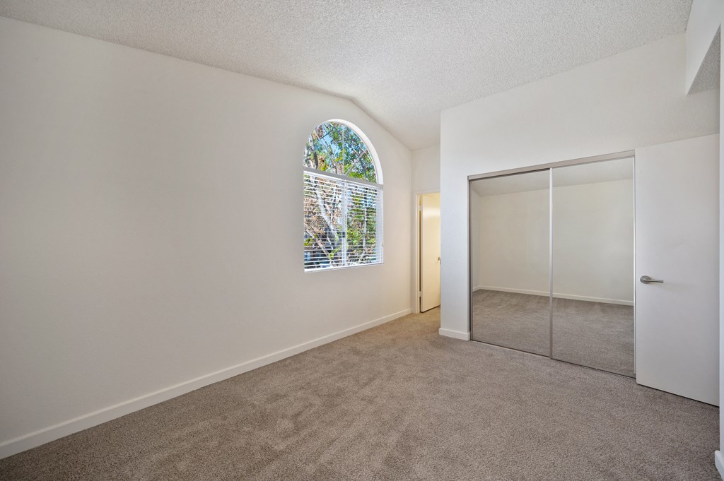 a living room with an arched window and a mirrored closet