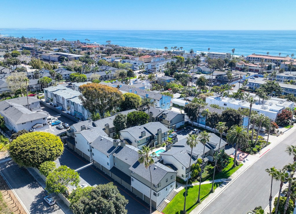 an aerial view of a neighborhood with houses and the ocean in the background