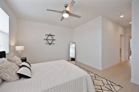 a white bedroom with a large bed and a ceiling fan