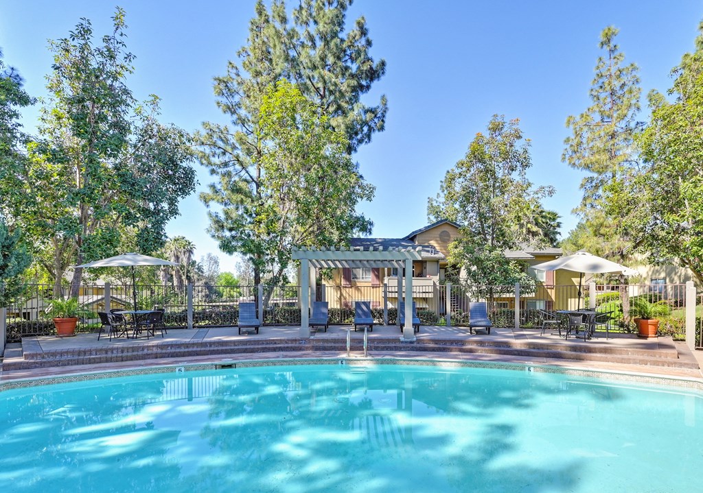 a swimming pool with trees and a house in the background