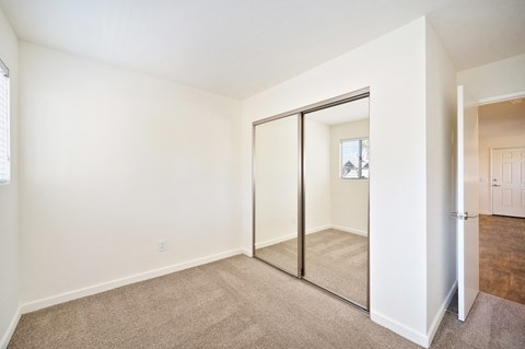 a bedroom with a mirrored closet door and a carpeted floor