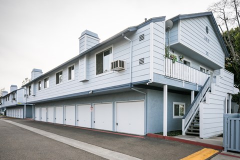 Blue and white building exterior with ground-floor garages.