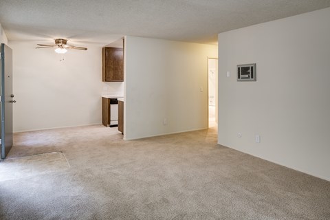 Carpeted apartment living room with view to dining room and kitchen.