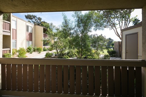Balcony overlooking courtyard with trees and landscaping.