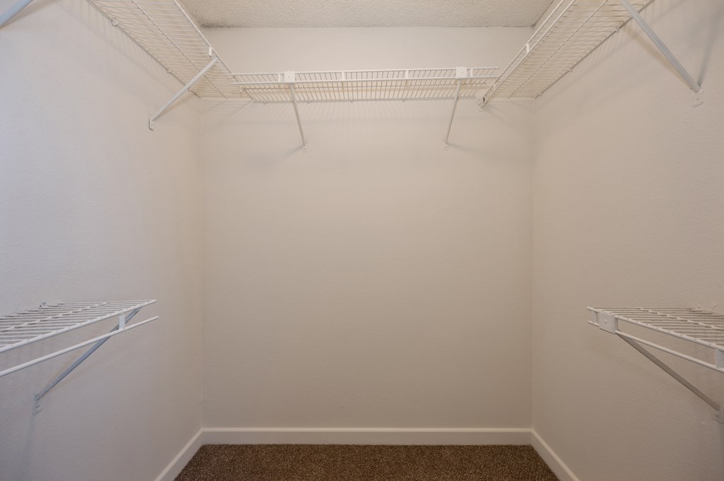 an empty closet with two shelves and two racks on the wall