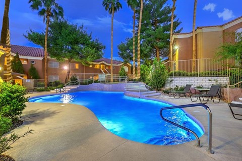 A swimming pool surrounded by palm trees and a fence.