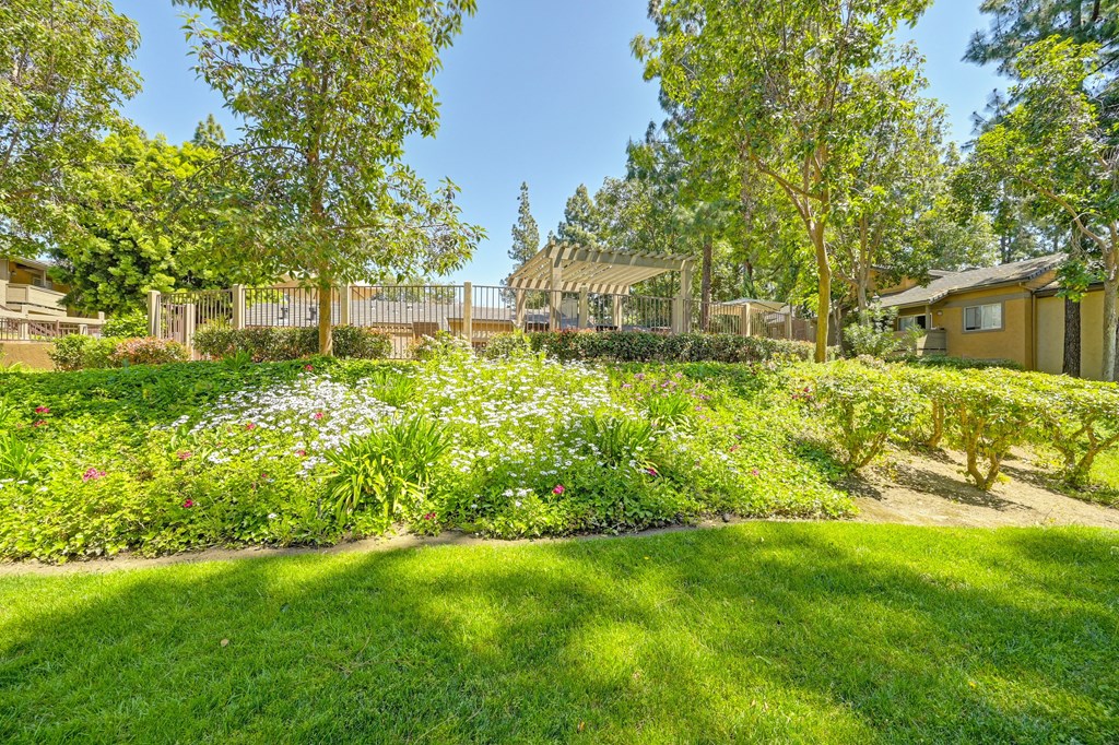 a garden with flowers and a fence and a house