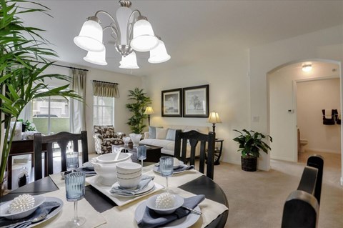 Carpeted dining room view with overhead light and view to sliding door balcony and interior hallway.