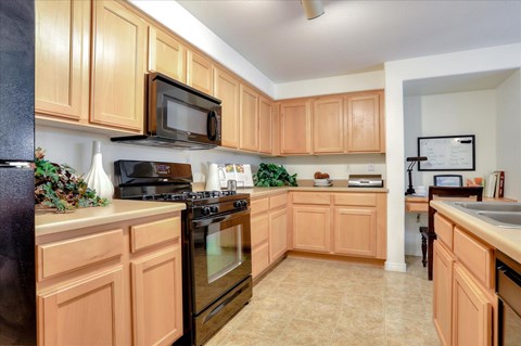 A kitchen with wooden cabinets and black appliances.