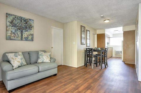 A living room with a grey couch and a painting on the wall.