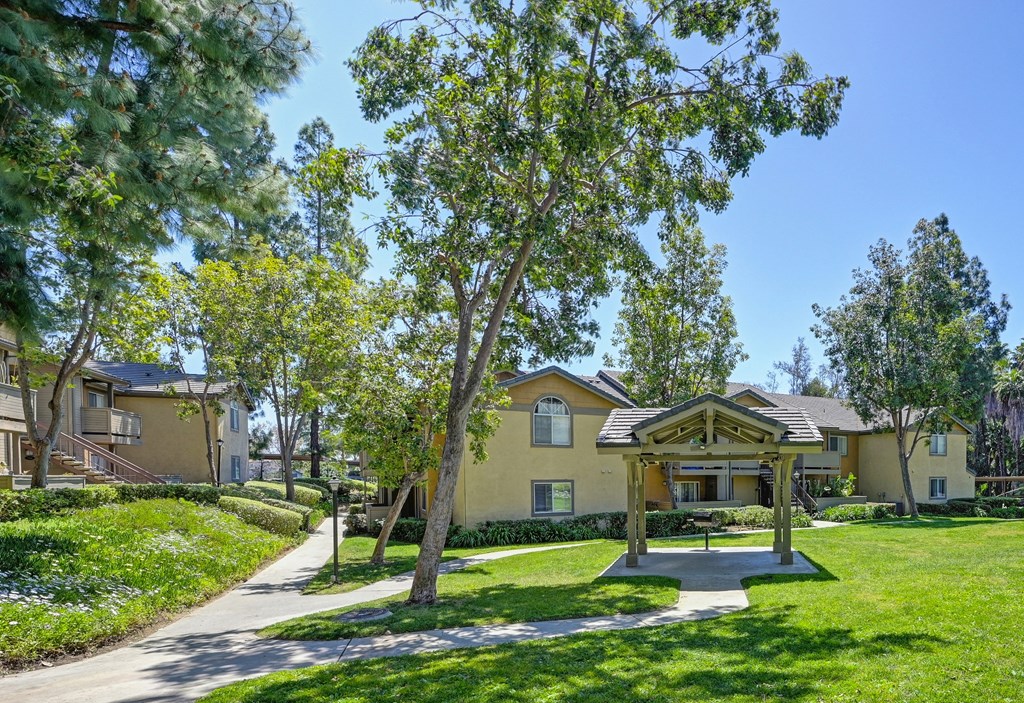 a park with a picnic area and houses in the background