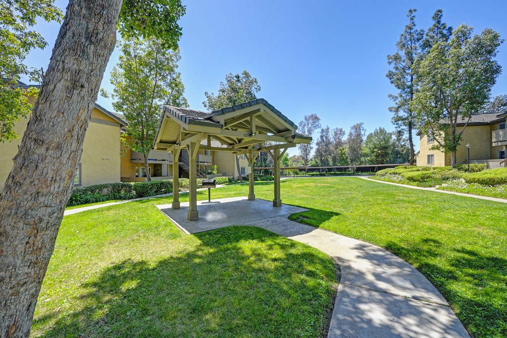 a gazebo in the middle of a yard with grass and trees