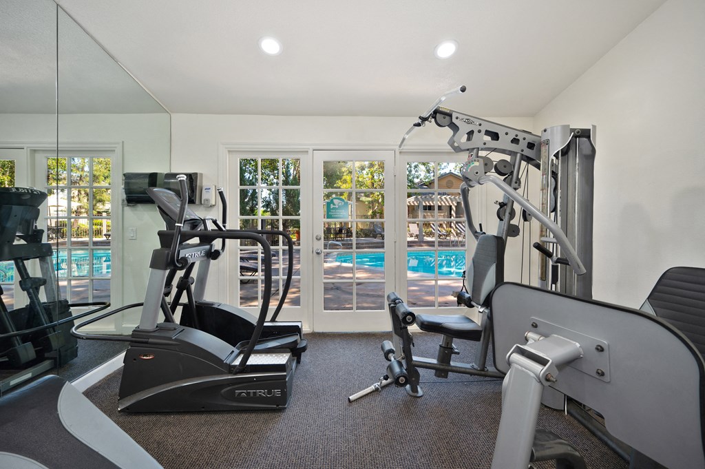the gym has plenty of equipment and a view of the pool