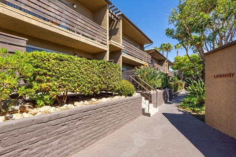 Exterior walkway with shrubs and brick exterior.