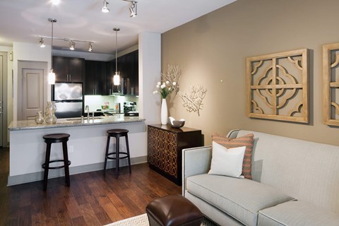 A modern kitchen with a bar area and a couch with pillows.