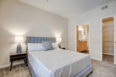A bedroom with a large bed and a wooden nightstand.