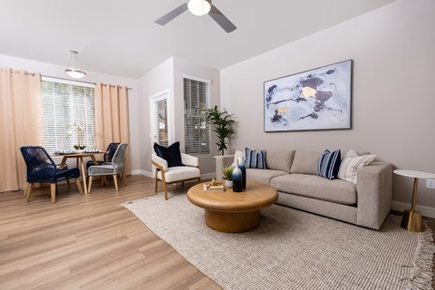 A living room with a couch, chairs, and a painting on the wall.