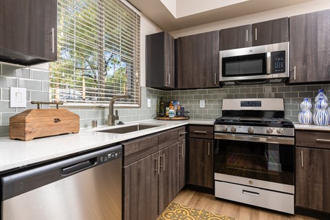 A modern kitchen with dark wood cabinets and stainless steel appliances.