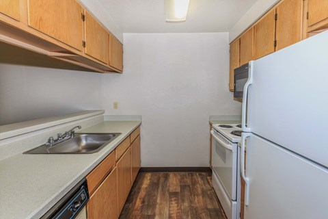 Kitchen with sink, dishwasher, microwave, refrigerator, and warm wood cabinets.