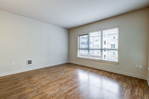 A room with wooden flooring and a window showing a building outside.