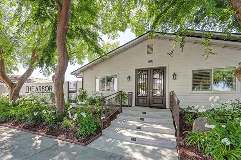 A leasing office with a black door and windows is surrounded by greenery.
