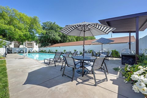 A patio with a table and chairs under an umbrella.