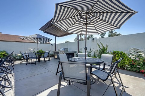 A patio with a table and chairs under a striped umbrella.