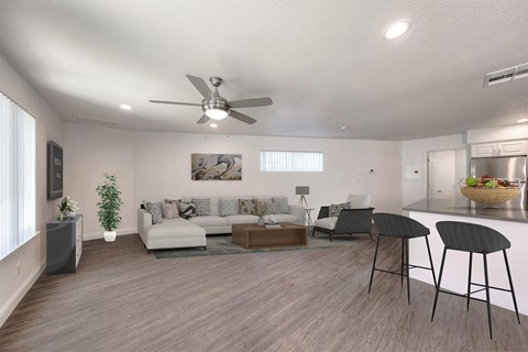 A living room with a white ceiling fan and a grey sofa.