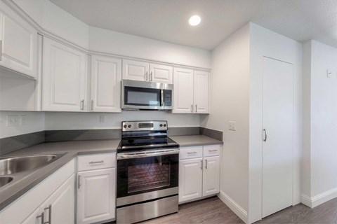A kitchen with white cabinets and a stainless steel oven.