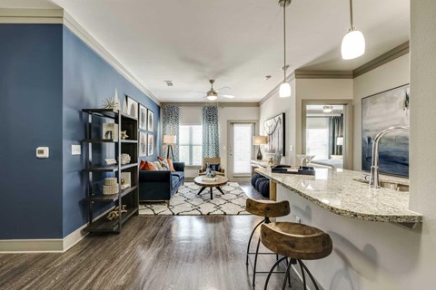 A modern kitchen with a blue wall and two wooden stools