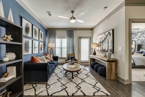 A living room with a dark blue sofa, a wooden coffee table, and a rug with a black and white pattern.