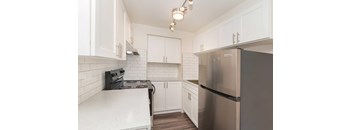 A kitchen with white cabinets and a stainless steel refrigerator and a black stove.