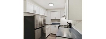 A kitchen with black appliances and white cabinets.