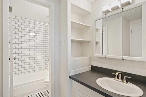 A white bathroom with a black counter top and a white sink.