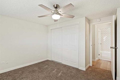 A room with a ceiling fan and a white closet door.