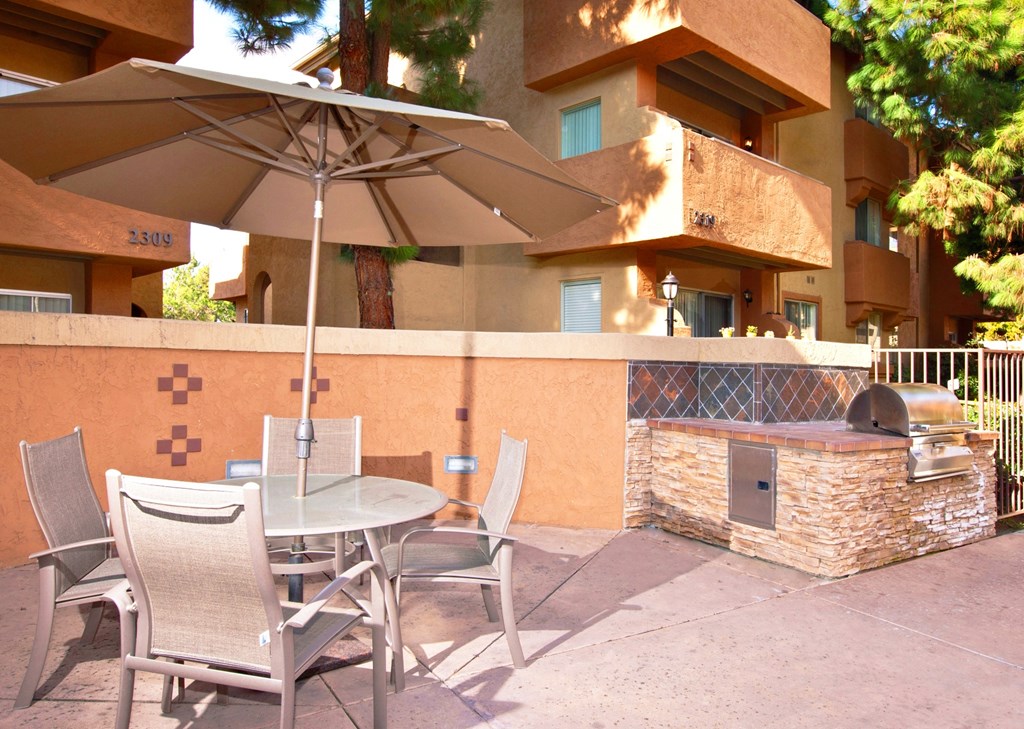 a patio with a grill and a table and chairs