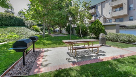 A wooden bench sits on a brick path in a grassy area.