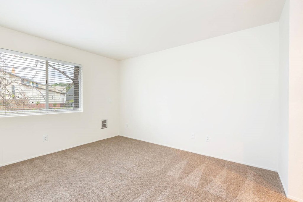 a bedroom with a window and a carpeted floor