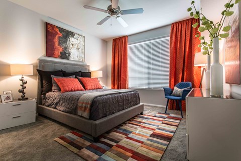 A bedroom with a bed, a chair, and a painting on the wall.