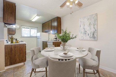 A dining room with a table set for four and a ceiling fan.