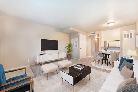 A living room with a white couch, a black coffee table, and a television.