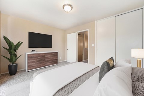 A modern bedroom with a large bed and a TV on the wall.