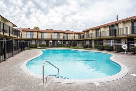 A swimming pool in a courtyard surrounded by a fence.