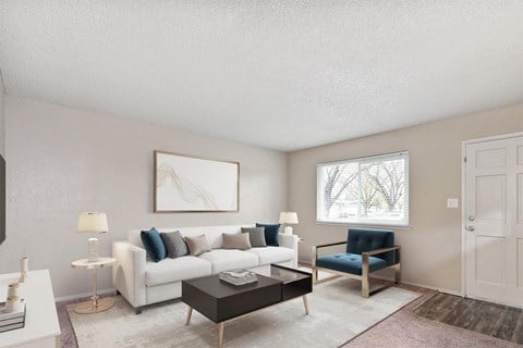 A living room with a white couch, a blue chair, and a painting on the wall.