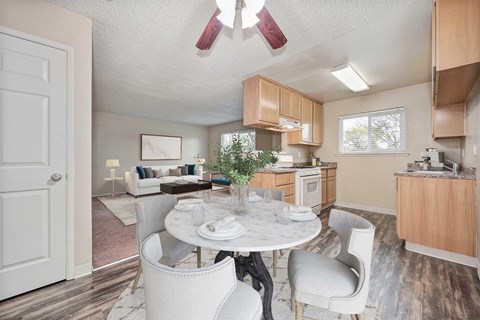 A white dining table with chairs and a potted plant in a kitchen.