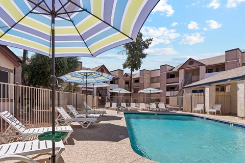 A pool area with sun loungers and umbrellas.